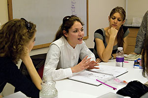 A group of students sits a table discussing an upcoming project